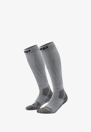 Pair of gray knee-high compression socks with reinforced heel, toe, and arch support areas, featuring black logo near the top.