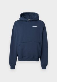 Felpa blu navy realizzata in morbido cotone. Presenta una tasca a marsupio, polsini a costine e un piccolo logo bianco sul petto. Texture liscia.