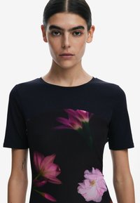 Kurzärmliges Oberteil mit einem dunklen Grundton und einem floralen Design in rosa und lila Farbtönen, glatte Textur und Rundhalsausschnitt.