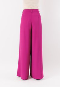 Pantaloni rosa a gamba larga in tessuto liscio, con vita alta e passanti per cintura. Il design presenta pieghe per un tocco di dettaglio e comfort.