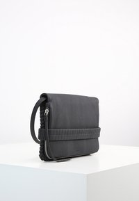 Borsa a tracolla in pelle nera con finitura testurizzata, chiusura con zip e dettaglio intrecciato sulla tracolla. Forma rettangolare con design minimalista.