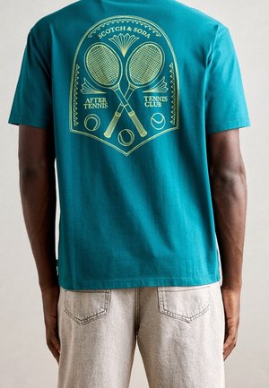 T-shirt sarcelle avec un motif jaune sur le thème du tennis, deux raquettes croisées, des balles de tennis et le texte « Scotch & Soda After Tennis Tennis Club » au dos.
