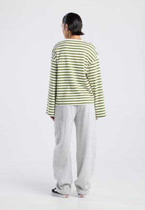 Groen en wit gestreepte overhemd met lange mouwen gecombineerd met losse grijze sweatpants, met een ontspannen pasvorm en zachte katoenen textuur.