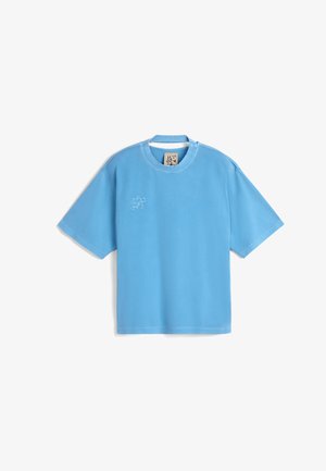 Camiseta de manga corta azul claro hecha de una tela suave. Presenta un cuello redondo y un pequeño diseño bordado en la parte frontal.