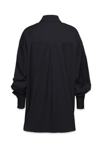 Fekete hosszú ujjú ing hátpleittel, széles gombos mandzsettákkal és klasszikus gallérral, hátulról, fehér háttér előtt.