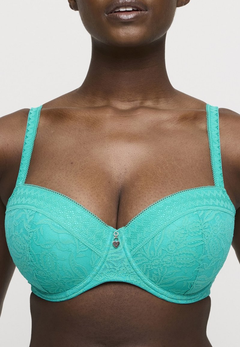 Turkos spets-bh med byglar, blommönster, justerbara axelband och en dekorativ hjärtcharm i mitten. Slät textur.