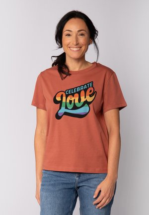 Korte mouwen, roestkleurig katoenen t-shirt met een veelkleurig grafisch ontwerp en de tekst "CELEBRATE Love" in een speelse lettertype.