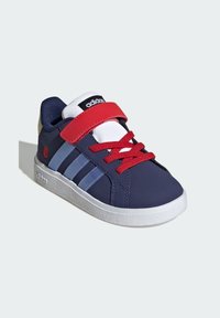 Marinblå sneaker med röda detaljer, vita snörningar och tre ljusblå ränder. Har ett kardborreband och en strukturerad vit sula.