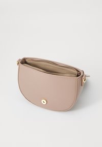 Borsa a tracolla in pelle beige con una texture liscia, chiusura a zip e dettagli dorati. Presenta una forma arrotondata e un pulsante a scatto esterno.