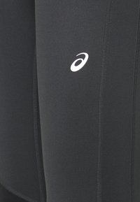 Leggings sportivi neri realizzati in tessuto elasticizzato, con logo bianco e cuciture piatte visibili. Texture liscia, design aderente.