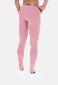 Svetloružové legíny vyrobené z elastického materiálu, s vysokým pásom a brandingom "Baker SPORT". Uplé a s hladkou textúrou, bez vzorov.