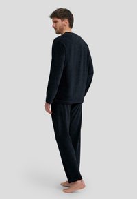 Conjunto de loungewear en azul marino oscuro, fabricado con un suave tejido texturizado. Camiseta de manga larga con cuello redondo y pantalones a juego con cintura elástica y corte relajado.