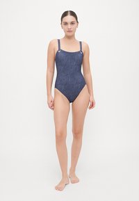 Navy één-pieces zwempak met een vierkante halslijn, verstelbare bandjes en decoratieve metalen accenten op de schouder. Glad textuur overal.
