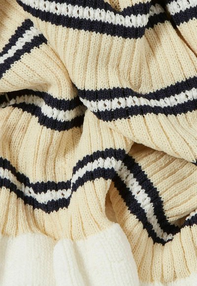 Suéter de punto con textura acanalada, color crema con rayas en azul marino y blanco, y una apariencia gruesa y acogedora.