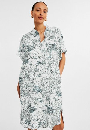 Korte mouwen, met kraag, jurk van witte stof met een blauw botanisch en landschap print, voorzien van zijsplitten en een ontspannen pasvorm.