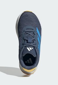 Zapatilla atlética de malla en color navy con rayas azules, detalles en blanco y suela amarilla. Presenta cordones y un cuello acolchado. Vista desde arriba.