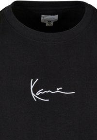 Svart bomullströja med en vit broderad signaturlogotyp på bröstet och en klassisk rundhalsdesign.