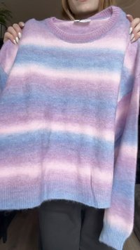 Suéter de punto con rayas horizontales en colores pastel de rosa, púrpura y azul. Cuello redondo y mangas largas con puños acanalados.