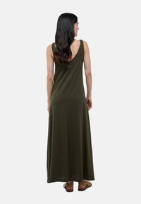 Robe maxi sans manches de couleur vert olive avec un dos en V, fabriquée en matériau doux, présentant une coupe décontractée qui tombe jusqu'à la cheville.
