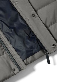 Chaqueta acolchada gris con cierre de cremallera que presenta un interior azul marino, botones de presión y una etiqueta "Polo Club" unida a la cremallera.