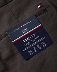 Slim-fit bruna chinos med strukturerad yta. Lappen har en marinblå bakgrund, vit text och brandingdetaljer i rött, vitt och blått.