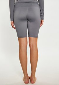 Szare, sportowe szorty do kolan o gładkiej fakturze, z wysokim pasem i subtelnymi detalami szycia. Noszone bez obuwia.