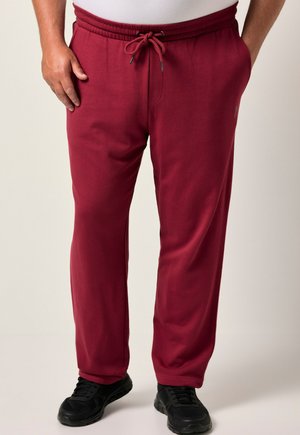 Bordeaux sweatpants met een elastische tailleband en verstelbare trekkoord, voorzien van zijzakken en een relaxte pasvorm. Draagt met zwarte sneakers.