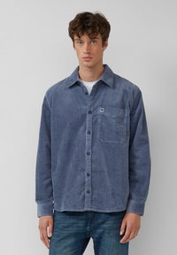 Blauwe corduroy shirt met een puntkraag, knoopsluiting aan de voorkant, lange mouwen, borstzak en subtiele verticale ribbelstructuur.