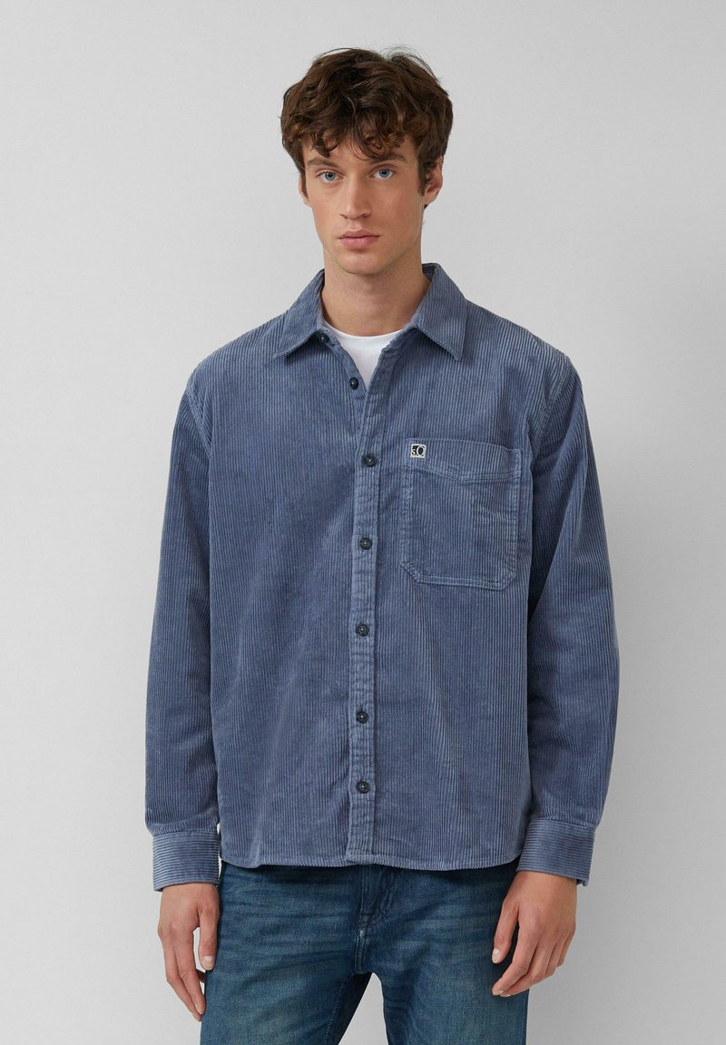 Blauwe corduroy shirt met een puntkraag, knoopsluiting aan de voorkant, lange mouwen, borstzak en subtiele verticale ribbelstructuur.