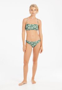 Zeleni bikini s uzorkom kremastih krugova, izrađen od glatkog materijala, s podesivim trakama i prilagođenim dizajnom.
