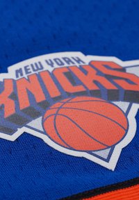 New York Knicks-logo met een oranje basketbal op een blauwe textuur achtergrond.