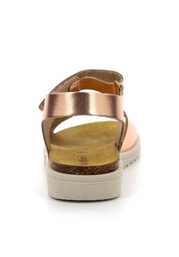 Sandalia de cuero en color rosa dorado con tira trasera, plantilla de un tono marrón claro y suela blanca texturizada. Cuenta con una mediasuela de corcho para mayor comodidad.