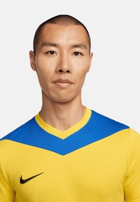 Maglia sportiva Nike con un corpo giallo e un colletto a V blu. Il tessuto appare liscio con un design aderente.