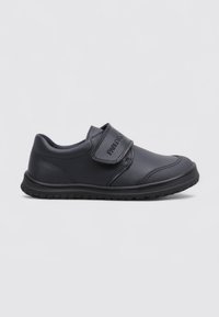 Chaussure d'enfants en cuir noir avec une seule sangle Velcro et une semelle en caoutchouc texturé, présentée de côté sur un fond uni.