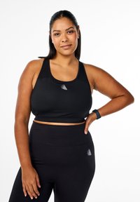 Svart atletisk crop top med låg halsringning och racerback-design, kombinerad med högmidjade svarta leggings som har en liten logotypdetalj.