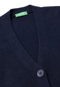 Námořnický vlněný svetr s V výstřihem, jednobodovým zapínáním a texturovaným pletením. Na štítku je napsáno "United Colors of Benetton."