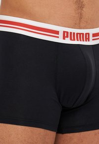 Crne bokserice sa bijelim pojasom s crvenim prugama i „PUMA“ logotipom, izrađene od glatkog materijala s uskim fitom.