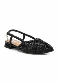 Zapatos planos negros trenzados con puntera afilada, correa en el tobillo y tacón pequeño. Hechos de un material brillante con detalles trenzados texturizados.