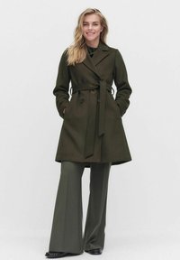 Olivgrön trenchcoat med bälte, dubbelknäppning, sidofickor och skräddarsydd passform. Bärs över matchande vida byxor.