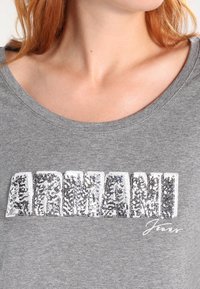 Szara krótki rękaw T-shirt z cekinowym logo "ARMANI" oraz słowem "Jeans" napisanym kursywą poniżej, z okrągłym dekoltem i miękką teksturą.