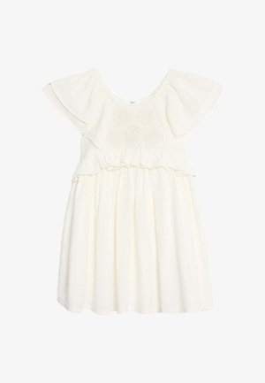 Robe blanche courte avec des manches volantes et un détail smocké au niveau de la poitrine, associée à des sandales en plastique rouge avec fermeture à boucle.