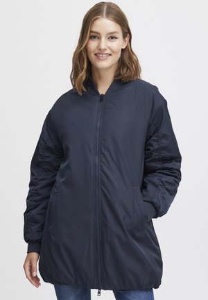 Navy blue padded jacket with a zippered front, ribbed cuffs, and side pockets; features a relaxed silhouette with slightly gathered sleeves.