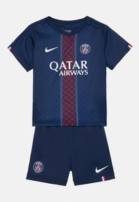 Temno modra nogometna majica in kratke hlače s rdečim geometrijskim vzorcem, belim logotipom "Qatar Airways" in Nike žigom. Vključuje podrobnost z francosko zastavo.