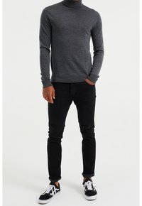 Šedý rolák s texturovaným pletením, kombinovaný s černými slim-fit džíny a černými teniskami s bílými detaily.