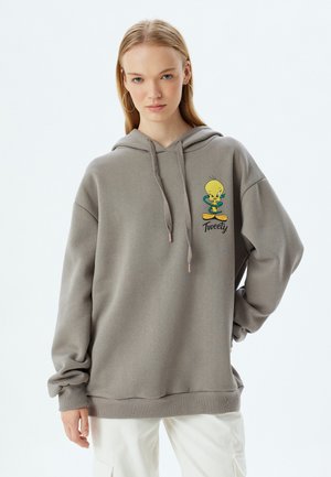 Sweatshirt gris avec capuche, présentant un graphique de l'oiseau Tweety en cartoon. Fait de tissu doux, il a une coupe décontractée et des poignets côtelés.