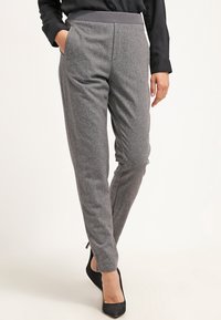 Pantaloni grigi su misura con un tessuto morbido e strutturato. Presentano un ampio elastico in vita e tasche laterali, progettati per una vestibilità slim.