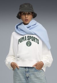 Balta sportinė džemperis su tamsiai žaliu "PUMA SPORTS" logotipu, šviesiai mėlyna šalikėlis ant kaklo, tamsiai pilka kibiro skrybėlė, šviesiai mėlynas fonas.