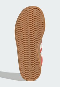 Gumová podrážka s vlnkovým vzorom, červený zvršok s bielymi pruhmi a štruktúrovaným povrchom pre lepšiu priľnavosť a odolnosť.