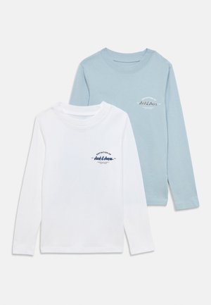 Twee T-shirts met lange mouwen: één wit en één lichtblauw, gemaakt van katoen, met een gedrukt logo op het linkerborstgebied van elk shirt.