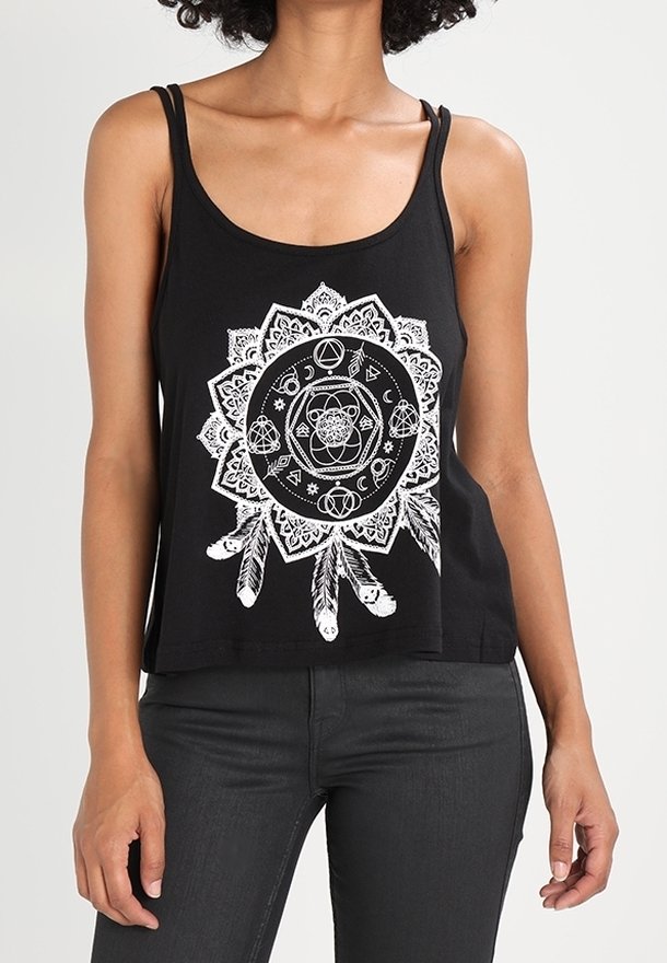 Débardeur noir avec un motif mandala blanc complexe présentant des formes géométriques, des symboles célestes et des plumes suspendues, porté avec un pantalon sombre.